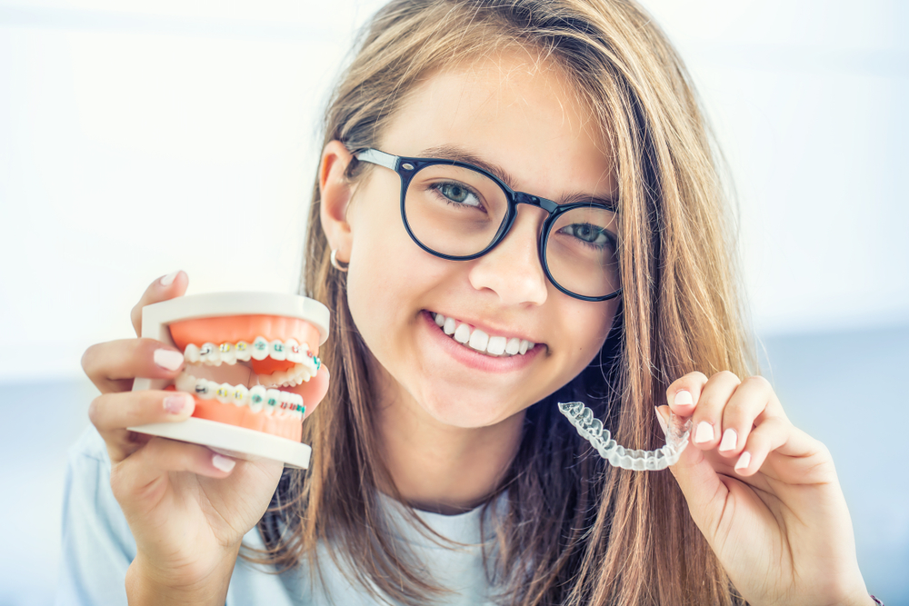 girl holding invisalign and braces