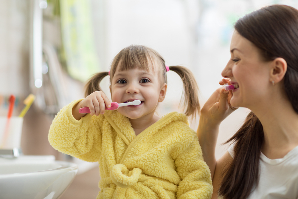 child and parent brushing teeth