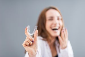 happy woman holding up Invisalign
